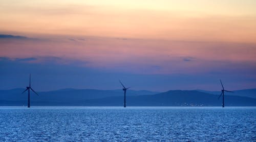 Offshore wind turbines operate at sunset off the Irish coast.