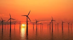 Wind turbines generating electricity offshore silhouetted by a golden sunset Wind turbines generating electricity offshore silhouetted by a golden sunset
