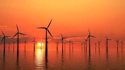 Wind turbines generating electricity offshore silhouetted by a golden sunset Wind turbines generating electricity offshore silhouetted by a golden sunset