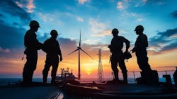 Silhouetted workers on a ship deck admire sunset-lit wind turbines. Silhouetted workers on a ship deck admire sunset-lit wind turbines.