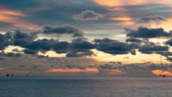 A handful of offshore infrastructures are seen in the far distance during sunset. A handful of offshore infrastructures are seen in the far distance during sunset.