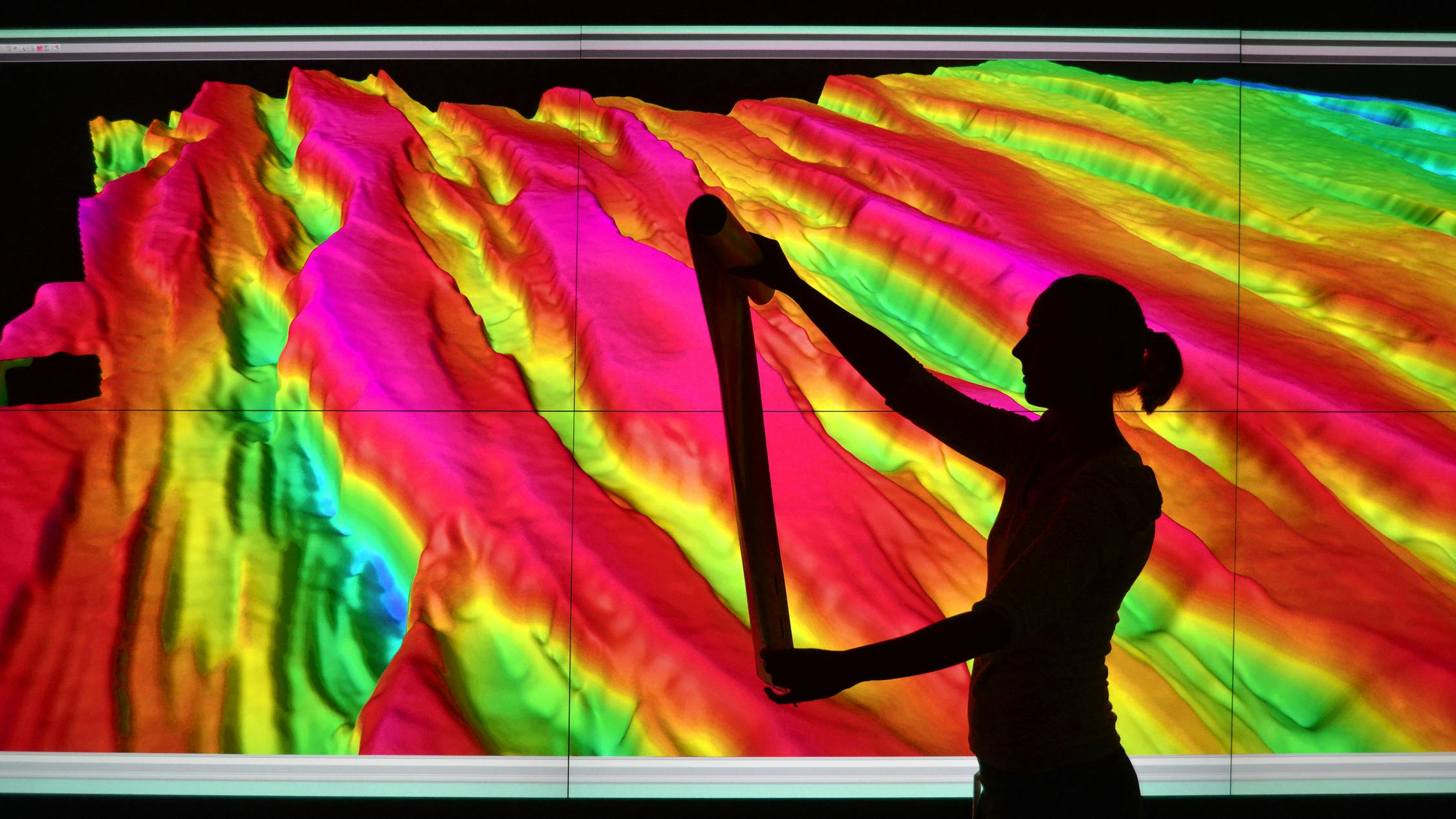 Female geoscientist examines print outs of seismic