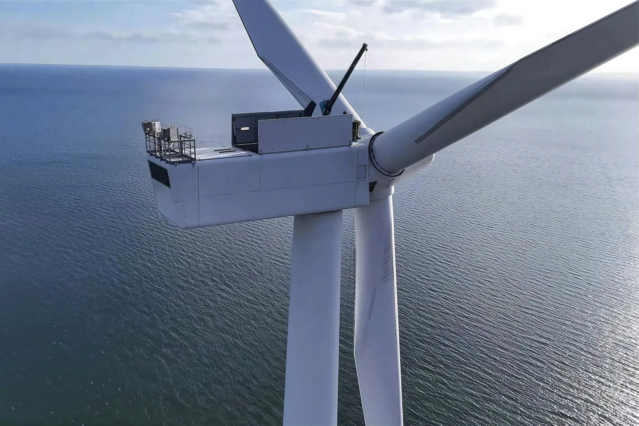 Aerial view of offshore wind turbine nacelle and blades over gray ocean