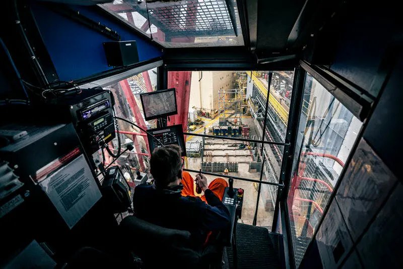 crew member monitors drilling operations from the control cabin aboard a Noble offshore rig