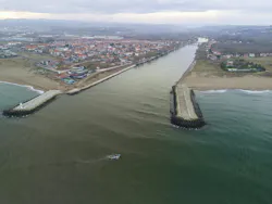 Drone view of a Turkiye coastal estuary, showcasing a small town nestled between the river and the ocean