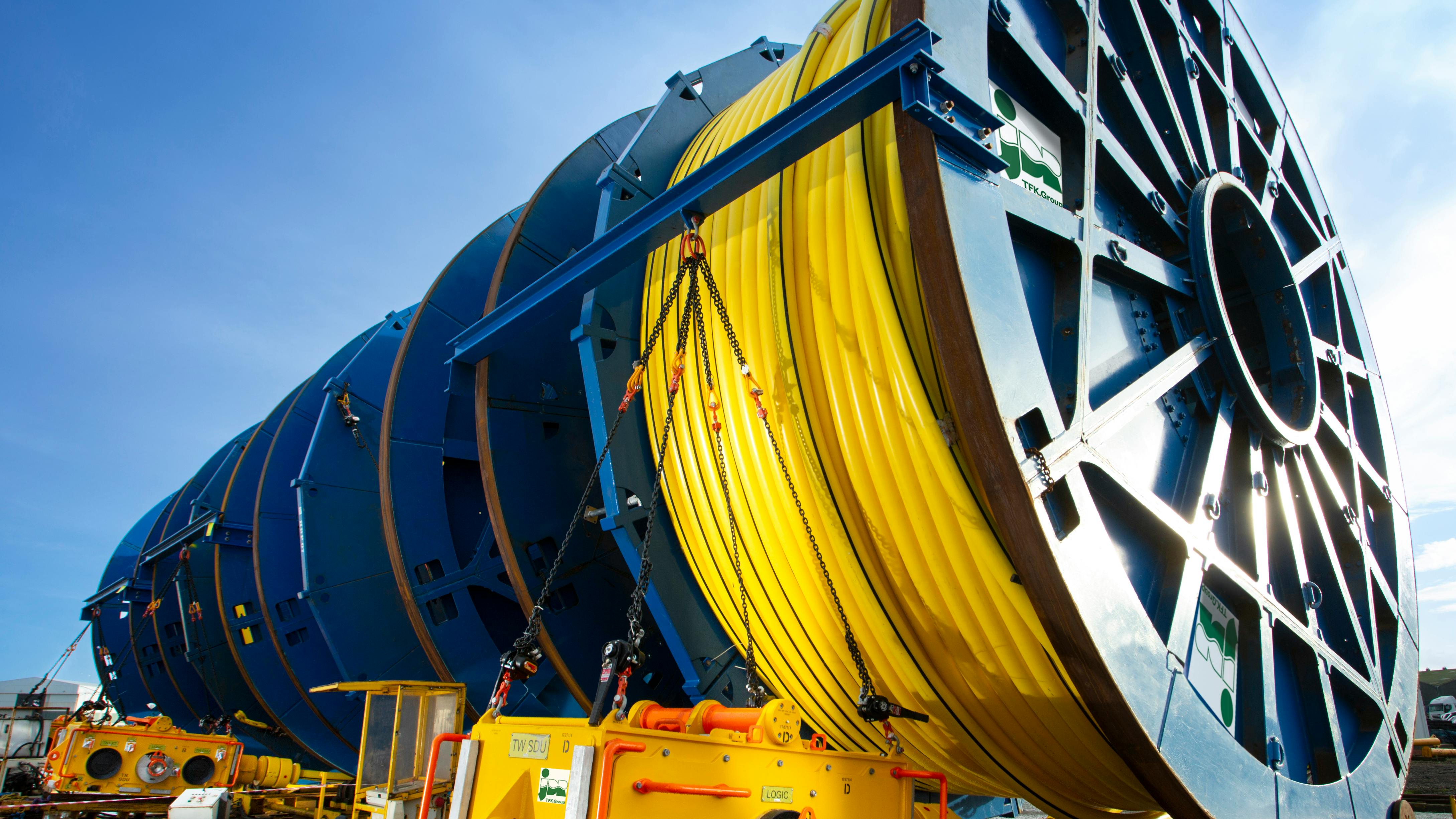 Large blue cable reels with yellow subsea cable in foreground