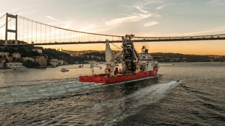 Subsea7 offshore construction vessel transiting beneath a suspension bridge